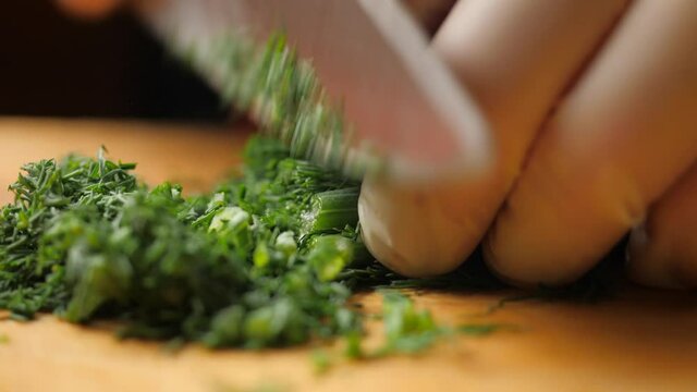 Chef cuts bunch of fresh dill on wooden cutting board. Diet and healthy food.