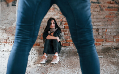 Violent man standing and threatens girl that sits on the floor with teddy bear in abandoned building