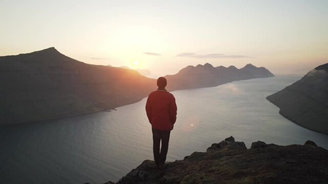 Hiker On Mountain Watching Sun Rise Over Klakkur