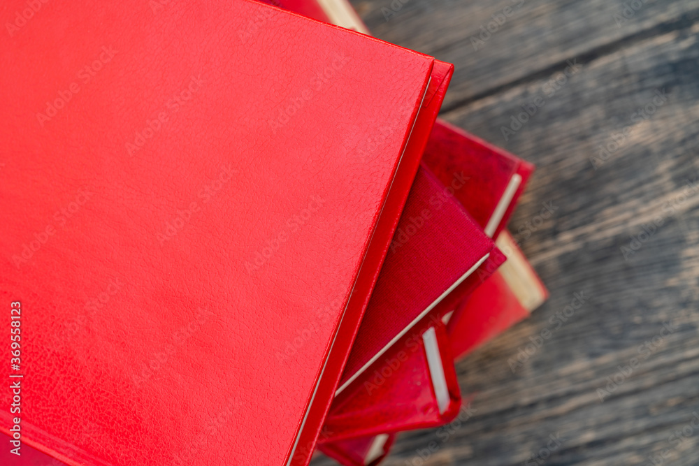 Wall mural Top view of a stack of red books on wooden table