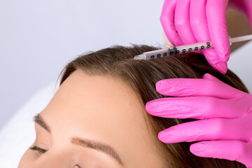 Cosmetologist does prp therapy against hair loss and anti-dandruff of a beautiful brunette woman in...