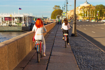 Two happy free women ride a Bicycle in the afternoon on the embankment