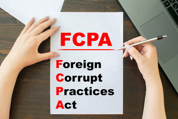 a girl writes an inscription on a sheet of paper Paper with words FCPA Foreign Corrupt Practices Act