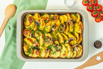 Potato wedges baked with mushrooms, herb oven roasted, with thyme, a close-up in a baking tray