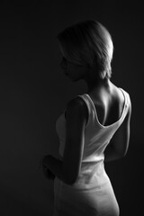  young sad woman looks away, a dark black and white photo. Stands sideways .
