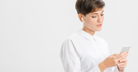 Fototapeta premium a young woman uses wireless headphones for a video call. white background in studio. online business meeting concept