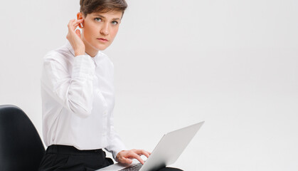  close portrait of a young businesswoman, which uses wireless headphones for a video call. white background in studio. online business meeting concept