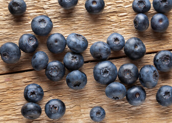 Fresh ripe blueberry heap on wooden background. Natural organic berries scattered on weathered wooden table, new berry harvest. Top view