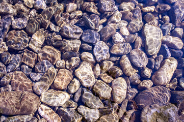 Pebble stone underwater close-up in sunlight. Natural background