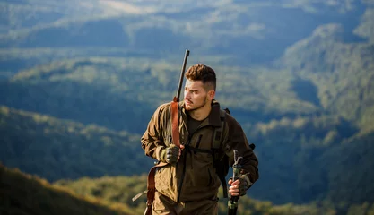 Tuinposter Hunt hunting rifle. Hunter man. Hunting period. Male with a gun. Hunter with hunting gun and hunting form to hunt. Shooter sighting in the target. The man is on the hunt © Yevhen