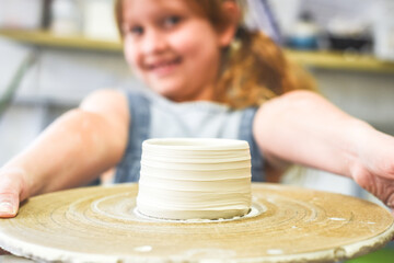 Fototapeta na wymiar Child holds up a bowl made during ceramic pottery making class