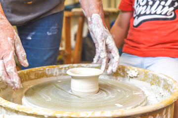 Children making pottery during ceramic lesson with clay