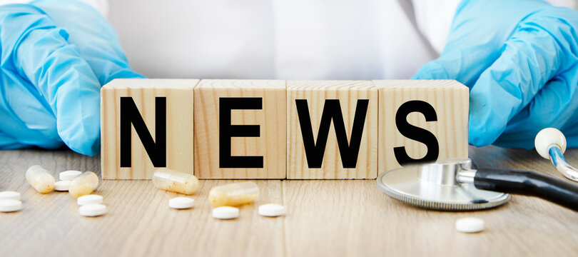The word NEWS on wooden cubes, the vra holds cubes. Nearby stethoscope and tablets. A medical concept.