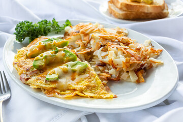 A view of a breakfast plate, featuring an omelet and home fries, in a restaurant or kitchen setting.