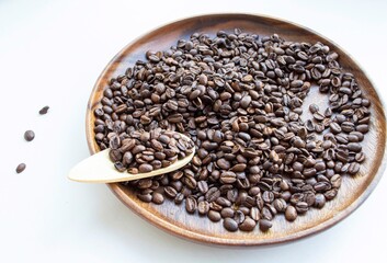 Coffee beans in a dish made of wood, on a light background