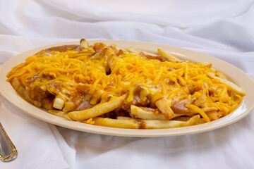 A view of a plate of chili cheese fries, in a restaurant or kitchen setting.
