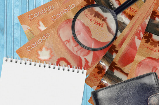 50 Canadian Dollars Bills And Magnifying Glass With Black Purse And Notepad. Concept Of Counterfeit Money. Search For Differences In Details On Money Bills To Detect Fake