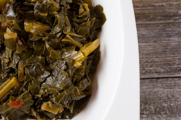 A top down view of a bowl of collard greens, in a restaurant or kitchen setting.