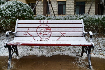 Bench with children's drawings on the snow covered in winter Christmas eve