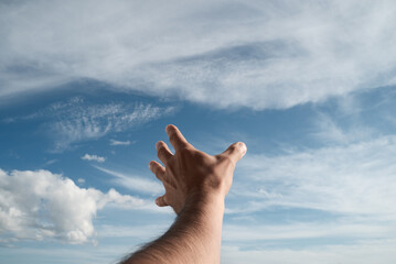 A hand reaching into the sky. Point of view. Sunlight.