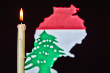 One light candle burning brightly and lebanon map with flag in the black background grunge sad style