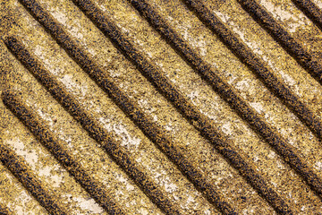 Corrugated concrete texture in yellow. Wavy concrete wall pattern. Close-up of yellow wavy surface, eliciting optical illusion. An old wavy surface on a concrete wall. Rough texture of paving slabs