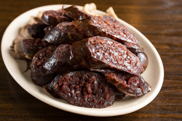 A view of a plate of blood sausage, in a restaurant or kitchen setting.
