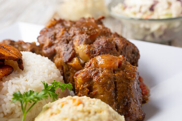 A closeup view of braised oxtail cuts, part of a plated entree, in a restaurant or kitchen setting.