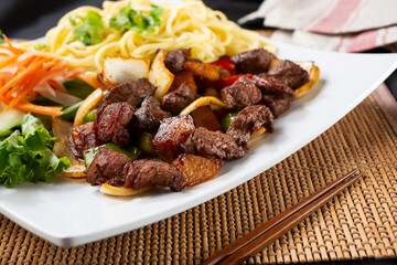A view of a plate of Shaking Beef, or Bo Luc Lac, in a restaurant or kitchen setting.