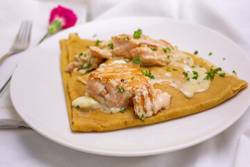 A view of a French crepe with salmon filet and cream sauce.