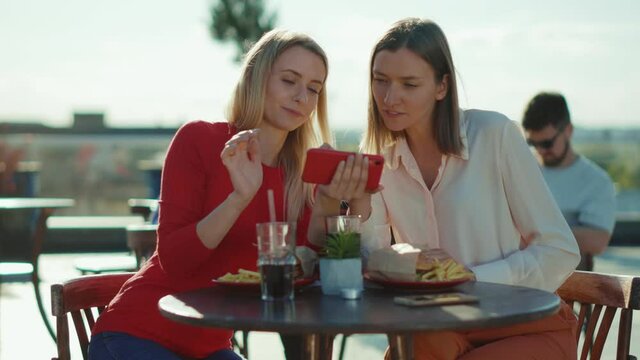 Attractive two women resting talking use phone drinking cocktail in summer cafe street sisters cafe casual city friendship models outdoors slow motion