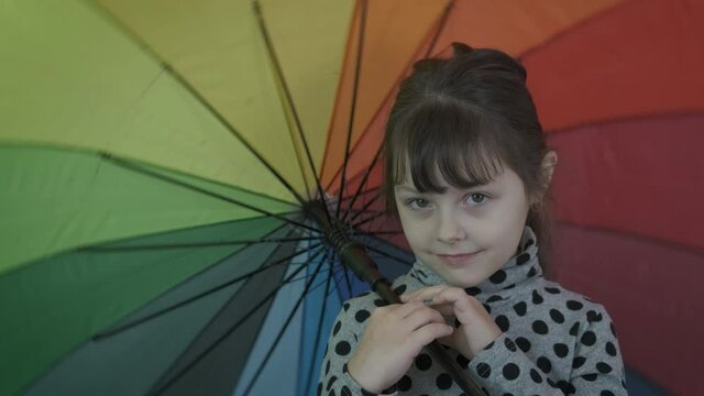 Colorful child smile in the room. Cute little girl with a multi-colored umbrella.