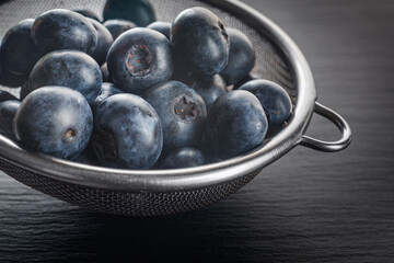 Group of fresh ripe blueberries in metal bowl. Close up view.