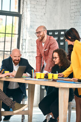 Beautiful business people are using gadgets, talking and smiling during the conference in office. Selective focus