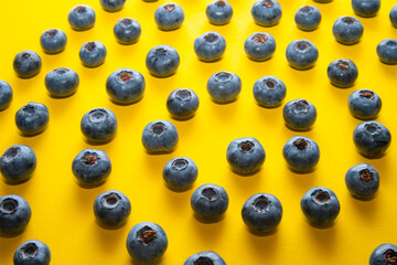 Blueberry pattern on yellow background. Ripe blueberries texture close up.