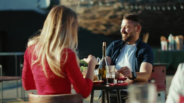 Happy young relaxing man and woman drinking cocktail smiling in street cafe time together date food girlfriend meal cheerful portrait slow motion