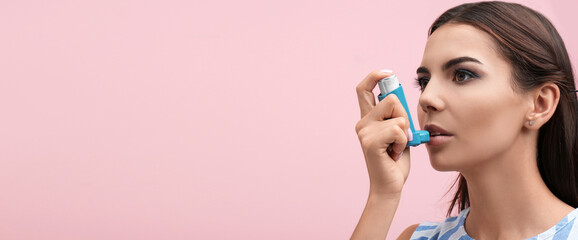 Young woman using asthma inhaler on color background, space for text. Banner design - obrazy, fototapety, plakaty