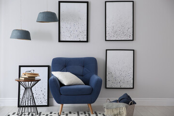 Beautiful artworks and comfortable armchair in stylish room. Interior design