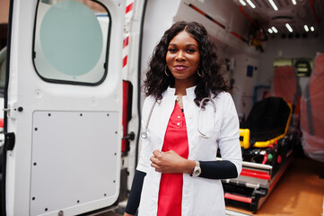 African american female paramedic standing in front of ambulance car.
