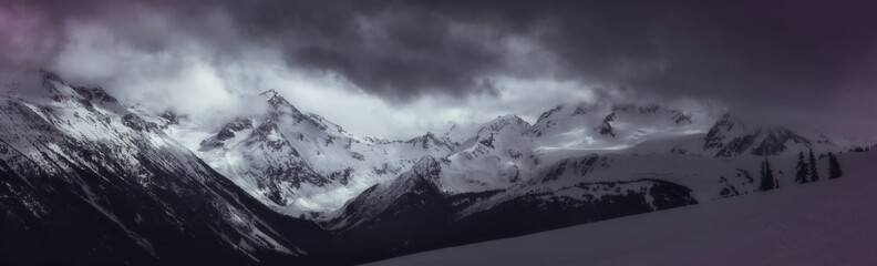 Moody mountain mist rising around snow covered peaks in Whistler backcountry