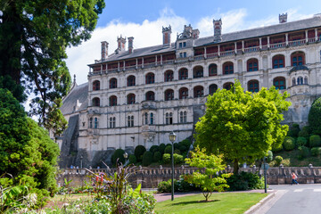 Castillo europeo con muchas ventanas, arboles y flores