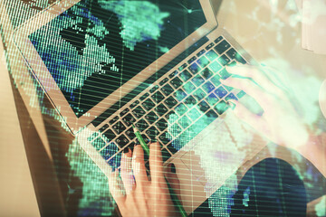 Double exposure of woman hands working on computer and financial theme hologram drawing. Top View. Business concept.