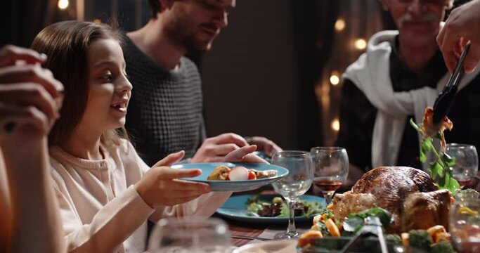 Large caucasian family celebrating thanksgiving day, chatting at dinner party table while eating roasted turkey and salads - celebration concept 4k footage