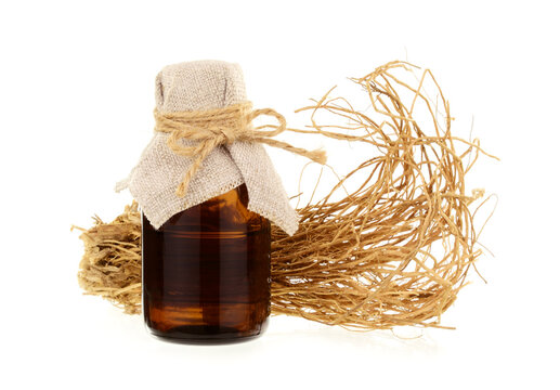 Vetiver Essential Oil Extract in a Bottle with Roots. Isolated on White Background.