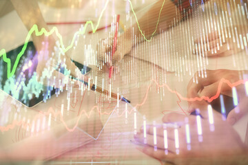 Double exposure of forex graph drawing and man and woman working together holding and using a mobile device. Trade concept.