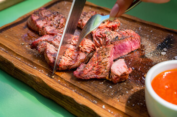 Grilled beef medallions served on a wooden kitchen board garnished with sauce