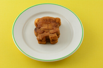 Monkey shaped animal soft cookie banana filled pastry on small dessert plate on yellow background
