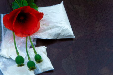 flowers and opium poppy heads next to packages of heroin, soft focus, toning