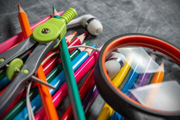 back to school: colorful schoolboy supplies lie on black chalkboard, short focus, partial blur