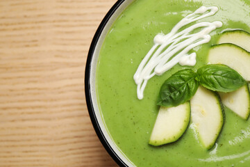Tasty homemade zucchini cream soup on wooden table, top view